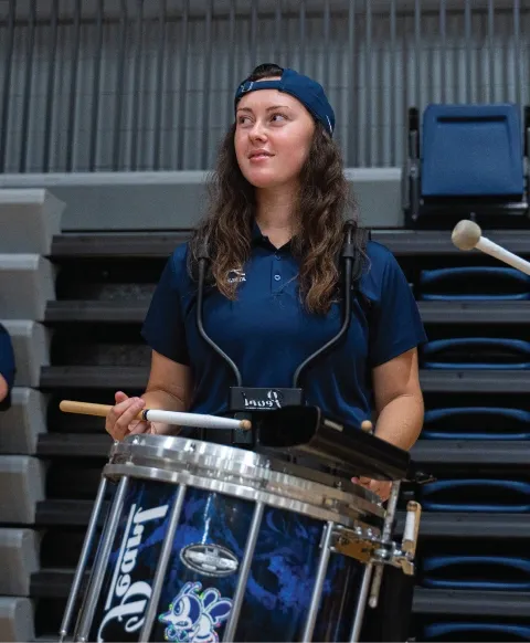 Student playing drums indoors.