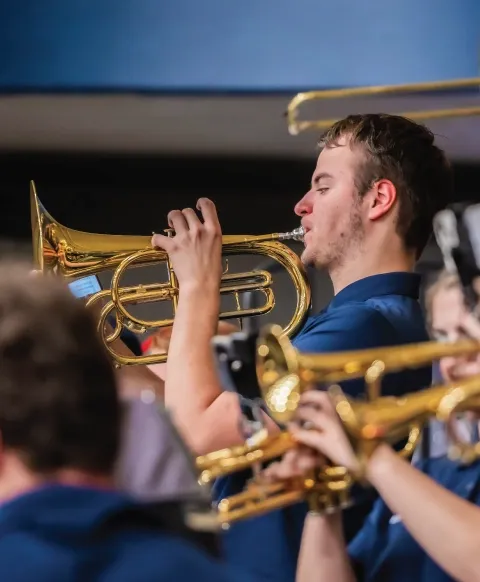 Member of pep band playing indoors.